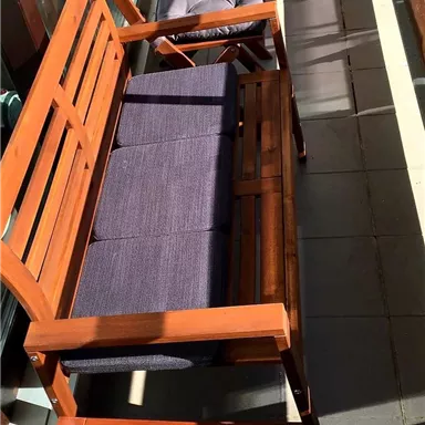 Ein Balkon mit zwei Holzsitzen. Die Möbel sind bequem und bieten Platz zum Entspannen.