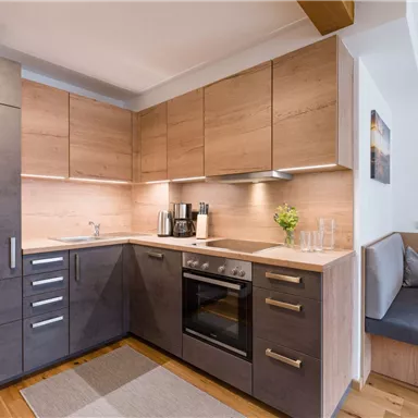 Eine moderne Küche mit Holz- und Metallelementen. Sie ist gut ausgestattet mit einem Herd, einer Spüle und einer gemütlichen Sitzecke.