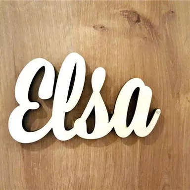 A decorative sign with the name "Elsa" made of light wood. The background is a wooden surface.