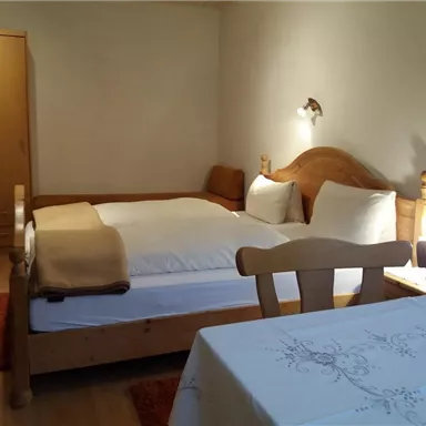 A cozy room with two beds and beautiful wood design. There is a table and a bright, inviting atmosphere.