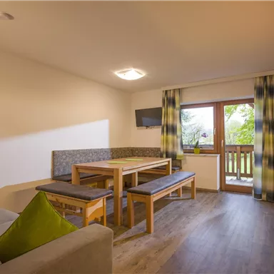 Eine moderne Wohnung mit einer gemütlichen Sitzecke und einem Essbereich. Große Fenster bieten einen Blick nach draußen.