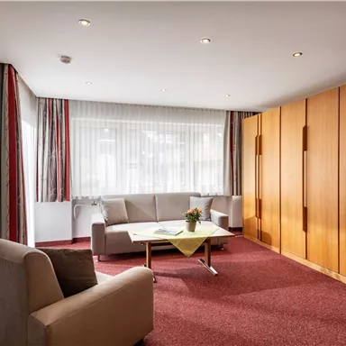 A cozy living space with two bright sofas and a table. Large windows provide plenty of daylight and a pleasant atmosphere.