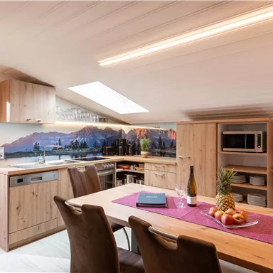 Modern kitchen in a cozy room with wooden furniture. Fresh fruit and a bottle of wine are on the table.