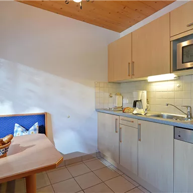 Eine moderne Küche mit Holzdetails und einem Tisch. Auf dem Tisch liegt ein Korb mit Brötchen.