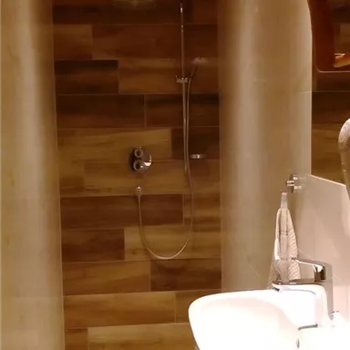 Eine moderne Dusche mit Holzverkleidung und einem großzügigen Waschbecken. Die Wände sind hell und freundlich gestaltet.