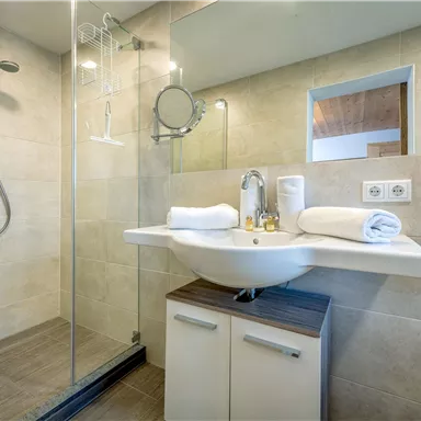 A modern bathroom with a glass enclosure and a shower. The neutral color scheme creates an elegant atmosphere.