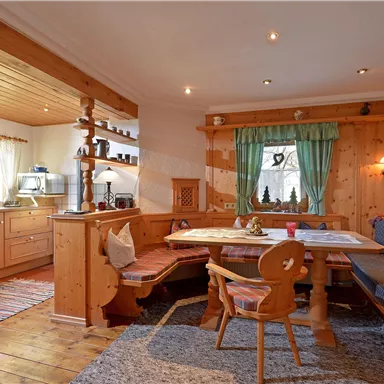 Ein gemütliches Wohnzimmer mit Holzverkleidung und einer Essgruppe. Die Küche ist offen und gut ausgestattet, mit einem einladenden Fensterblick.