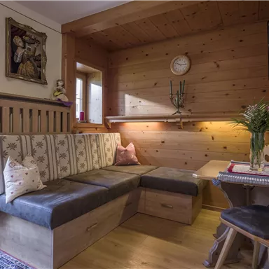 A cozy living space with wood paneling and a comfortable sofa. A vase with flowers is on the table and a television is mounted on the wall.