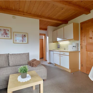 A cozy interior with a bright seating area and a modern kitchenette. The wooden paneling and decorations create a warm atmosphere.