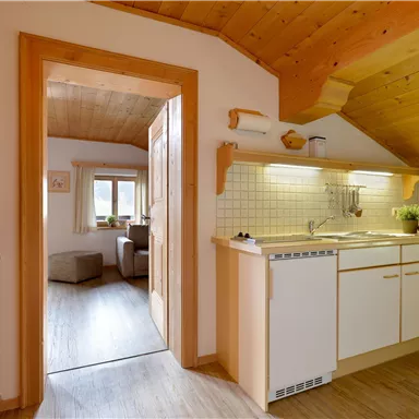 A bright, inviting kitchen with wood paneling and modern appliances. In the background, a cozy living area is visible.