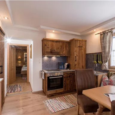 Eine gemütliche Ferienwohnung mit Holzmöbeln und einer kleinen Küchenzeile. Der Raum ist hell und einladend, ideal für einen entspannten Aufenthalt.