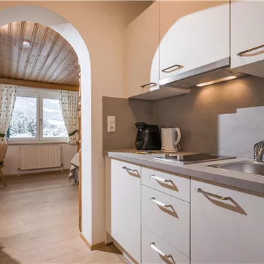 Eine moderne Küche mit hellen Schränken und einem kleinen Fenster. Der Raum ist freundlich und gut beleuchtet.