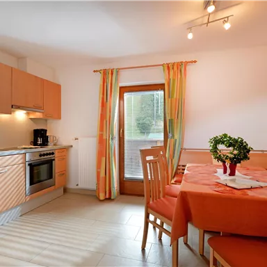 A bright kitchen with modern appliances and a dining area. The table is beautifully set, and the windows let in plenty of light.