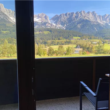 A beautiful view of the mountains and the green landscape from the balcony. The sun is shining and the sky is clear.
