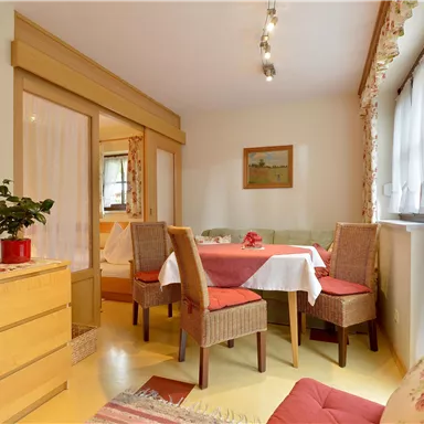 Ein gemütlicher Essbereich mit einem Tisch und Stühlen. Die Wände sind hell und mit dekorativen Bildern geschmückt.