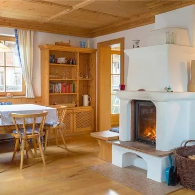A cozy dining room with wooden furniture and a fireplace. Large windows provide plenty of natural light.