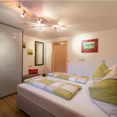 Ein gemütliches Schlafzimmer mit zwei Betten und einem modernen Design. Sanfte Beleuchtung und harmonische Farben schaffen eine einladende Atmosphäre.