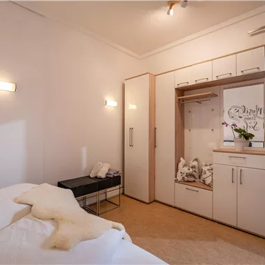 Ein modernes Schlafzimmer mit einem Doppelbett und einem Schrank. Das Zimmer ist hell und freundlich, mit einer eleganten Einrichtung.