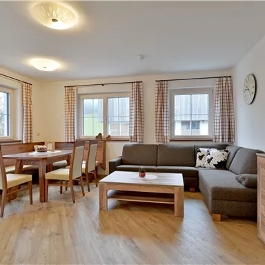 A cozy living room with a dining area and a comfortable couch. Bright windows create a friendly atmosphere.