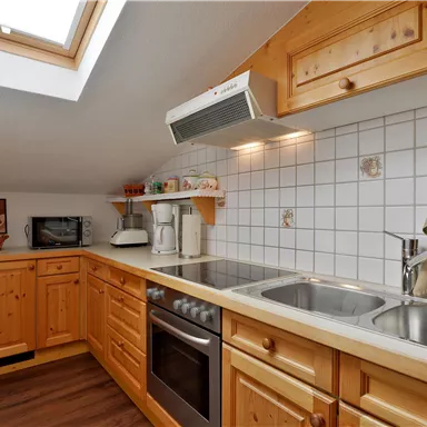 Eine moderne Küche mit Holzschränken und weißen Fliesen. Das Dachfenster sorgt für viel Tageslicht.