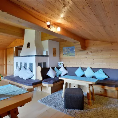 Ein gemütlicher Wohnraum mit Holzverkleidung, einer Feuerstelle und bequemen Sitzgelegenheiten. Der Raum ist hell und einladend, ideal zum Entspannen.