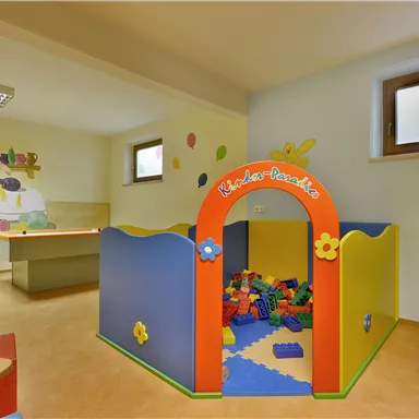 A colorful play area for children with a play tent and building blocks. Cheerful murals can be seen on the walls.