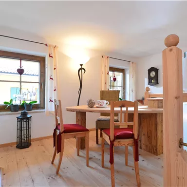 An inviting reception area with a wooden table and red chairs. Bright windows create a friendly atmosphere.