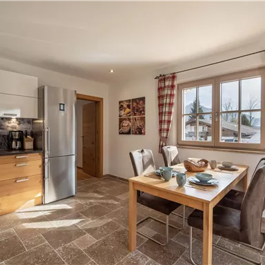 Eine moderne Küche mit Holzmöbeln und einem Esstisch. Der Raum ist hell und lädt zum Verweilen ein.