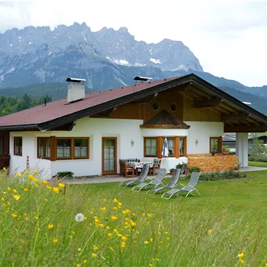 Ein gemütliches Haus mit einem großen Garten und Blick auf die Berge. Die Landschaft ist grün und einladend, perfekt für Entspannung im Freien.