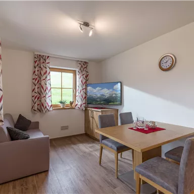 A cozy living space with a dining table and chairs. A window provides natural light and a friendly atmosphere.