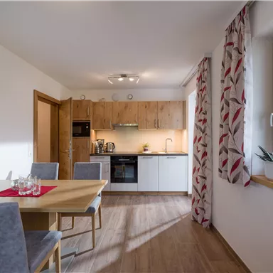 A modern kitchen with wooden furniture and a dining table.
A lot of light comes through the windows, creating an inviting atmosphere.