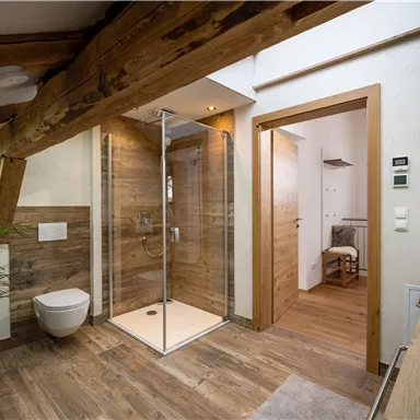 A modern bathroom with wooden elements and a glass shower. Bright walls and a beautiful floor create an inviting atmosphere.