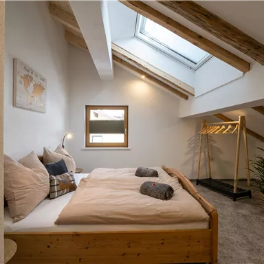 A cozy bedroom with a large bed and wooden details.  
Large windows let in plenty of light and create an inviting atmosphere.