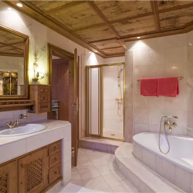 Ein elegantes Badezimmer mit Holzdecken und modernen Armaturen. Es verfügt über eine Badewanne und eine Duschkabine sowie einen großen Spiegel.