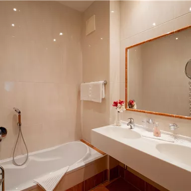 A modern bathroom with a bathtub and two sinks. The mirror reflects the bright and elegant design.