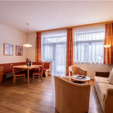 Bright living room with a cozy sofa and a dining area. Large windows provide plenty of daylight.