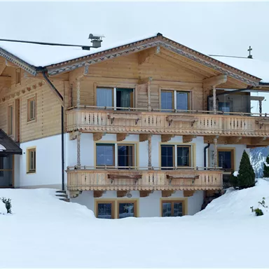 A cozy wooden house in the mountains, surrounded by snow. The balcony offers a beautiful view of the winter landscape.