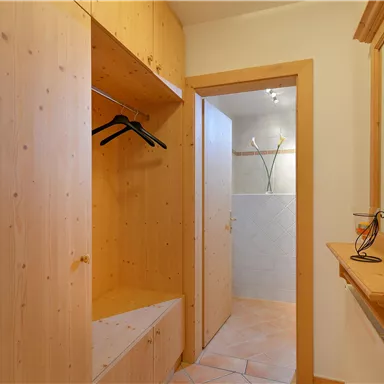 A bright entrance area with wooden furniture. The room features a coat rack and a mirror.