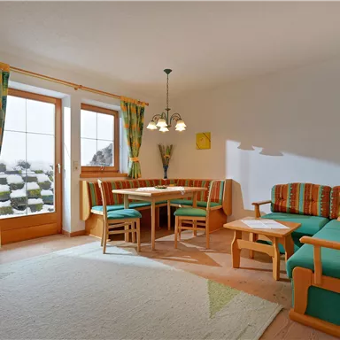 A cozy living room with colorful furniture and a dining table.  
Large windows provide plenty of natural light and an inviting atmosphere.