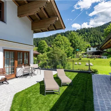 A beautiful garden with loungers and a relaxing atmosphere. The surroundings are green and surrounded by mountains, perfect for relaxation.