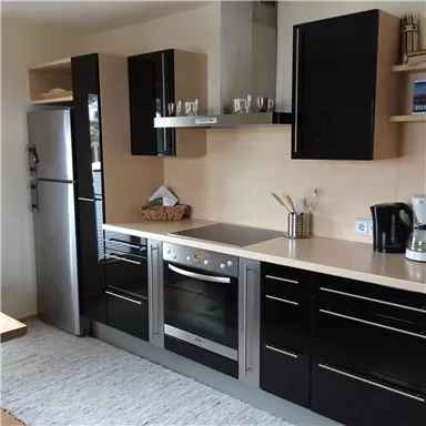 A modern kitchen with black furniture and stainless steel appliances. The room is bright and tidy.