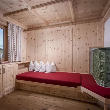 A cozy room with wooden paneling and a red sofa. A window offers a view of the landscape.