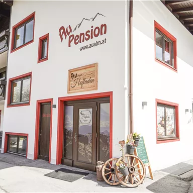 A cozy guesthouse with red and white exterior paint. In the foreground, there is a rustic sign and a wagon wheel decoration.