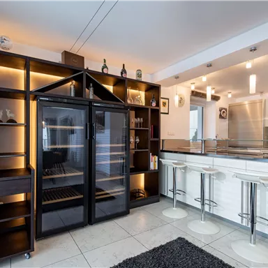 Eine moderne Küche mit einem eleganten Kochbereich und einem offenen Regal. Der Raum ist gut beleuchtet und hat ein stilvolles, zeitgemäßes Design.