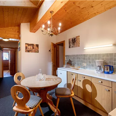 Eine moderne Küche mit Holzdetails und einem runden Tisch steht im Mittelpunkt. Die Wände sind hell und es gibt ansprechende Dekorationselemente.