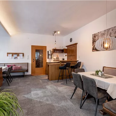 A cozy interior with tables and chairs. In the background, there is a counter and decorative elements on the walls.