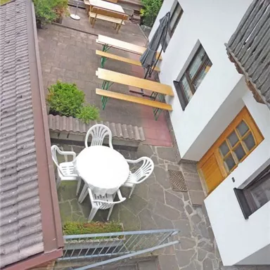 A cozy outdoor area with a round table and chairs. In the background, there are several benches and a snug atmosphere.