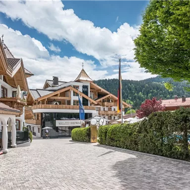 A quiet street with charming houses. In the background, there are idyllic mountains and a blue sky.