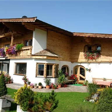 A beautiful, traditional house with wooden elements and colorful flowers. It is located in a green environment and has an inviting atmosphere.