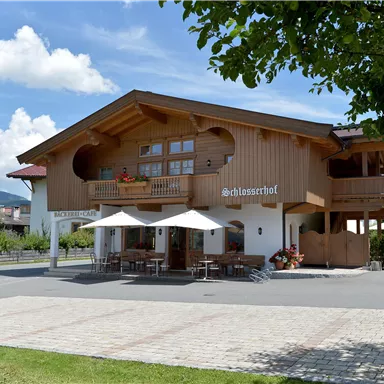 Ein gemütliches Holzhaus mit Balkon und Sonnenschirmen im Freien. Umgeben von einer schönen Landschaft und einem klaren blauen Himmel.